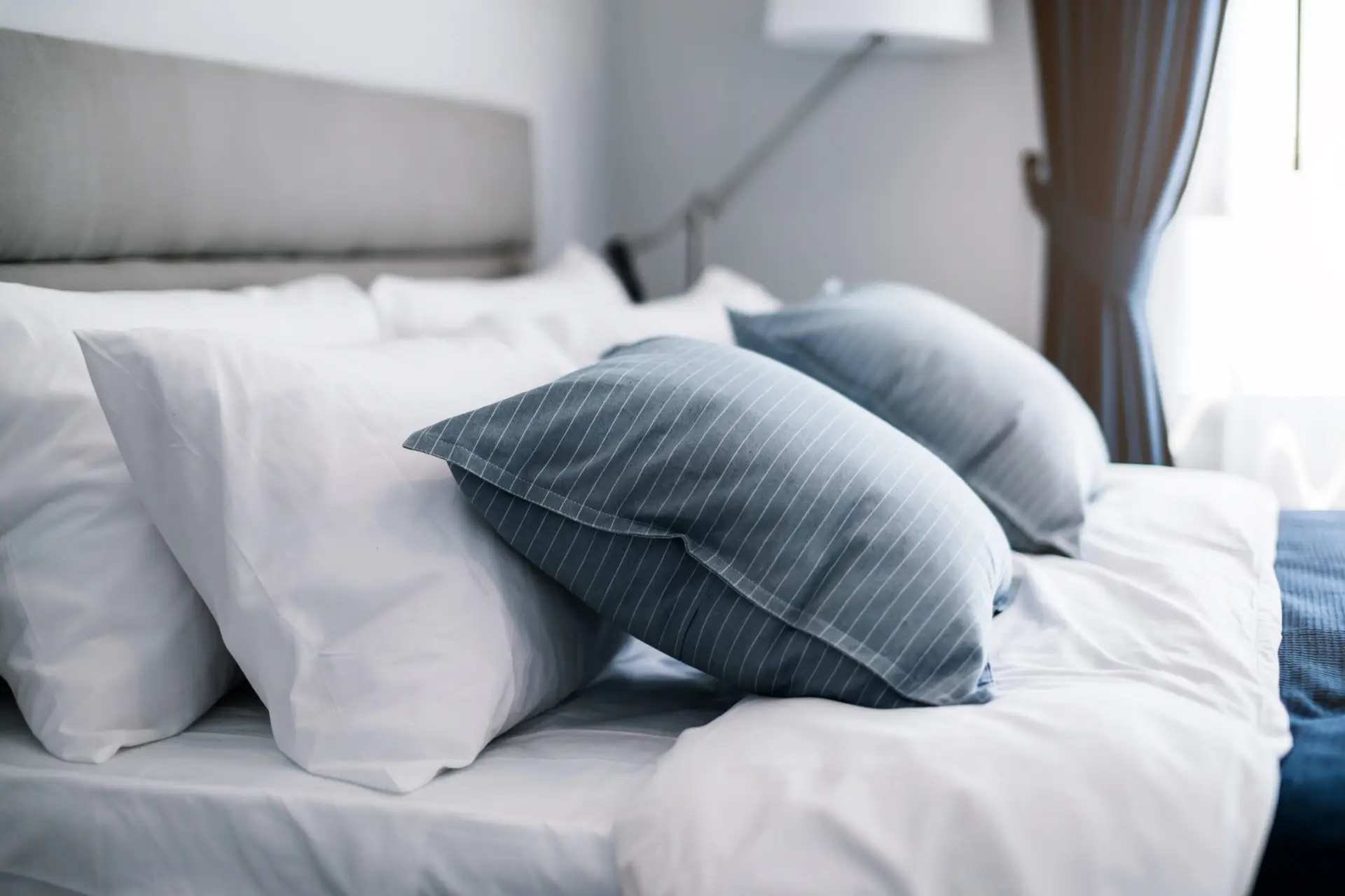 Bed maid-up with clean white pillows and bed sheets in beauty room. Close-up. Lens flair in sunlight.